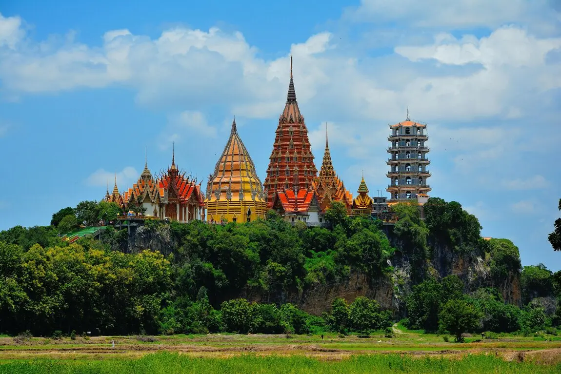 Ein Tempel in Thailand Auf einem Berg steht ein Tempel in Thailand, umgeben von grüneWäldern und Wiesen.